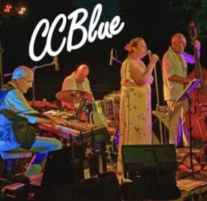 Een vierkoppige band staat 's avonds op het podium, met een pianist, drummer, zanger en staande bassist. CCBlue staat er in groot wit schrift boven.